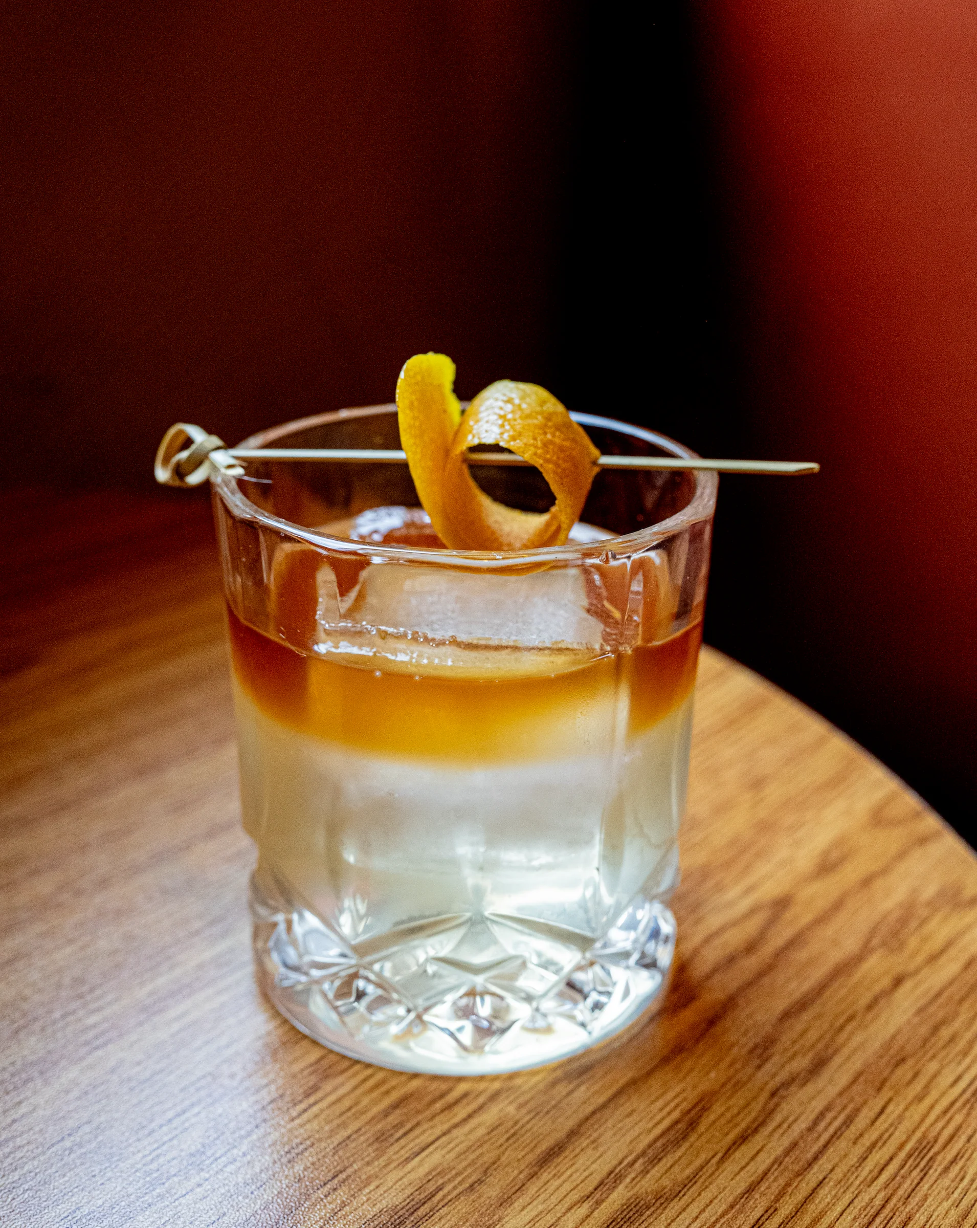 Old fashioned with an orange peel on a wooden table
