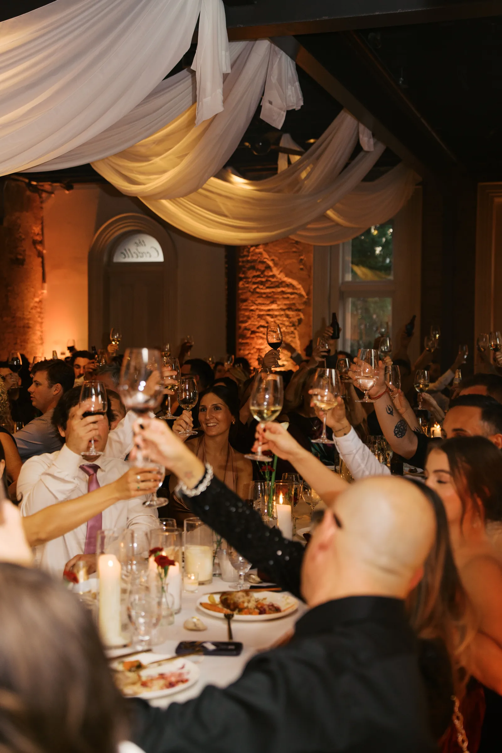 Guests raising glasses in a toast at the wedding dinner