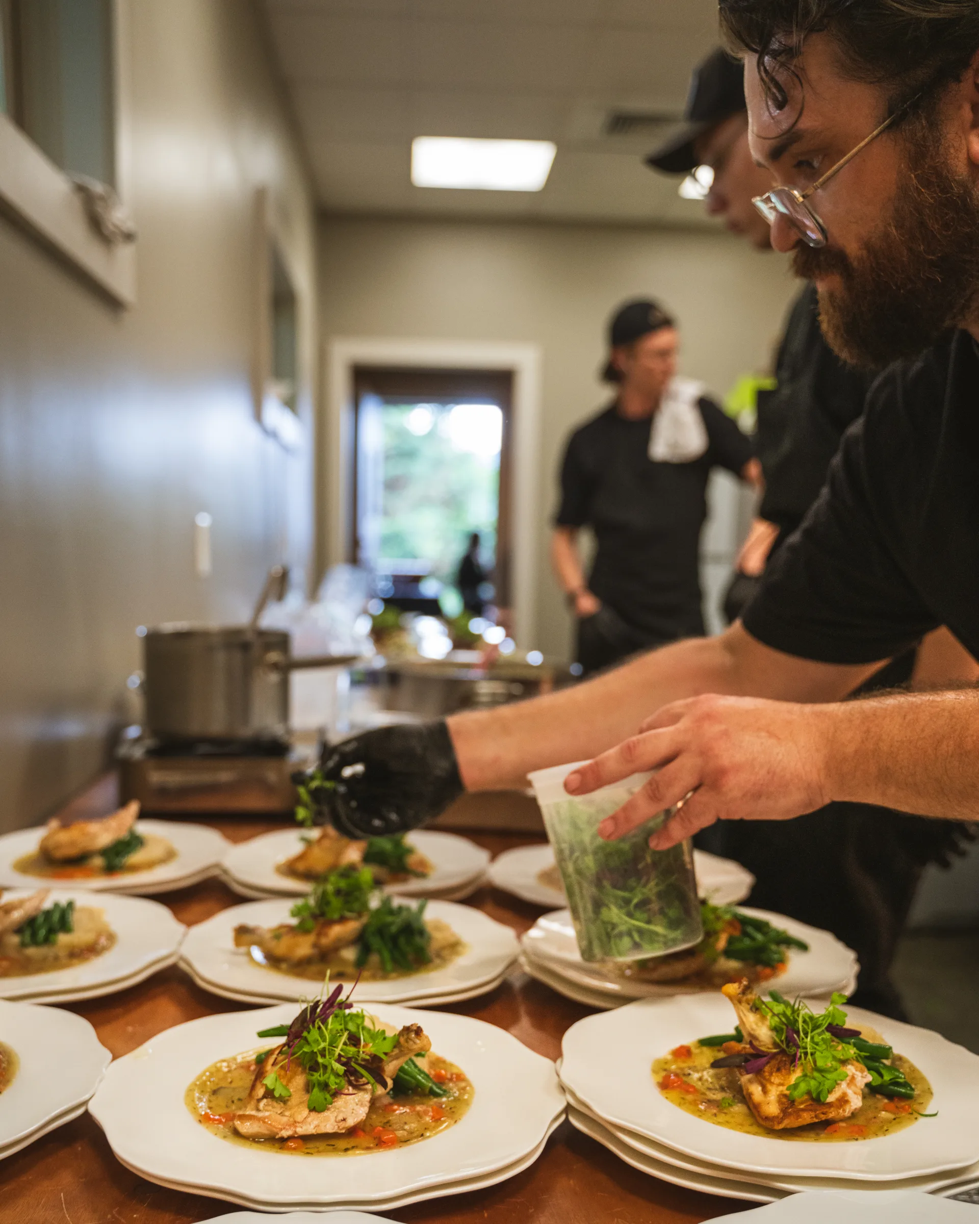 Chef plating a row of entrées in a venue kitchen